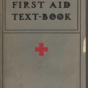 Puede incluir: Un libro rectangular gris titulado AMERICAN RED CROSS FIRST AID TEXT-BOOK con un símbolo de cruz roja en el centro y la palabra REVISED impresa cerca de la parte inferior. La portada presenta texto negro dentro de un borde rectangular negro.