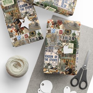 May include: Two rectangular gifts wrapped in collage-style paper featuring Noah Kahan imagery, text including Season of the Sticks, and Northern Attitude. Each package is tied with twine and a white star or heart-shaped gift tag.