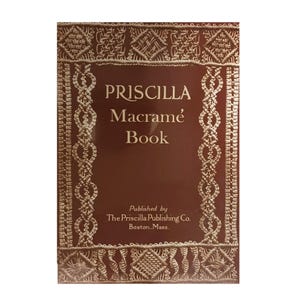 May include: A rectangular book with a deep maroon cover featuring a cream-colored macramé pattern border. The text reads PRISCILLA Macramé Book, Published by The Priscilla Publishing Co. Boston, Mass. The design includes intricate knotted rope motifs.