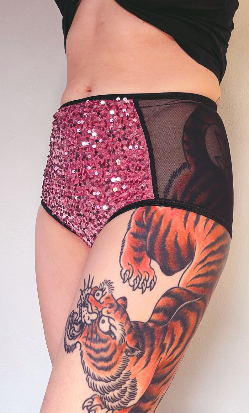Puede incluir: Ropa interior de cintura alta de lentejuelas rosas y malla negra con una banda el&aacute;stica negra. La ropa interior tiene un tatuaje de tigre en la pierna.