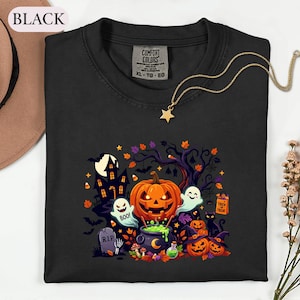 May include: A black t-shirt featuring a graphic print of a Halloween scene with a jack-o'-lantern, ghosts, a haunted house, a black cat, and a cauldron. The shirt has a Comfort Colors label at the neck with text including XL-TG-EG.