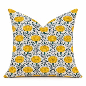 May include: A square throw pillow featuring a repeating pattern of bright yellow marigold flowers with green stems and leaves on an off-white background. The floral design is arranged in vertical columns across the entire surface of the pillow.