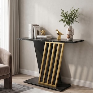 May include: A black marble console table with a gold-toned metal base featuring vertical slats. The table surface holds a stack of books, a gold star-shaped ornament, a gold bird figurine, and a white ceramic vase containing green foliage.