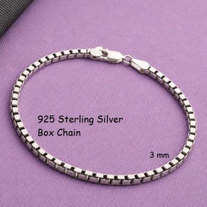 May include: A 925 sterling silver box chain bracelet with a lobster claw clasp. The chain features square-shaped links and has a width of 3 mm. The text 925 Sterling Silver Box Chain and 3 mm are clearly visible on the image surface.