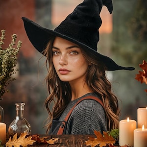 May include: A black velvet pointed hat with a wide, slightly drooping brim. The hat features a tall, conical crown that curves at the top. The material has a soft, textured appearance, providing a deep black color throughout the entire structure.