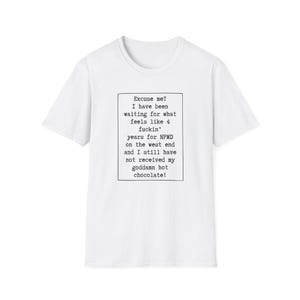 May include: A white short-sleeved t-shirt featuring a black rectangular border containing the text: Excuse me? I have been waiting for what feels like 4 fuckin' years for NPMD on the west end and I still have not received my goddamn hot chocolate!