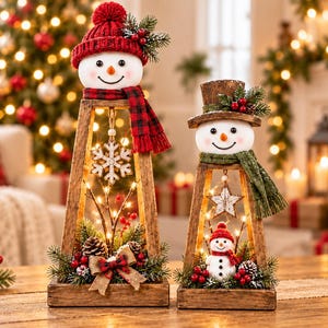 May include: Two wooden, pyramid-shaped Christmas decorations featuring snowman heads. The taller one wears a red knit hat and scarf, while the shorter one wears a brown top hat and green scarf. Both contain warm LED lights, pinecones, and berries.