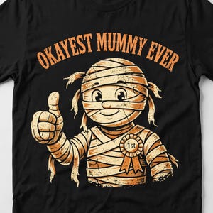 Close-up of the Okayest Mummy Ever print on a black t-shirt, showing the mummy artwork and pun lettering in crisp detail.