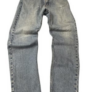 May include: A pair of light blue denim jeans with a faded wash, featuring a button fly closure, five pockets, and frayed, distressed hems at the bottom of the legs. The fabric shows signs of wear with lighter areas on the thighs and knees.