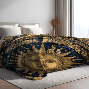 Peut inclure: Un jeté de lit bleu marine et doré orné d'un grand visage de soleil central avec des rayons, entouré de motifs célestes incluant des étoiles et des lunes. La couverture est posée sur un lit avec des oreillers blancs et une tête de lit grise.