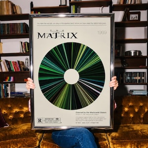 Könnte beinhalten: Ein gerahmtes Filmplakat für The Matrix, 1999, mit einer zentralen kreisförmigen Grafik aus strahlenden grünen und schwarzen Linien. Der Text enthält den Titel, das Zitat You take the red pill, you stay in Wonderland und die Filmcredits.