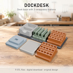 Puede incluir: Base de escritorio DOCKDESK con 3 estaciones intercambiables. El conjunto incluye una base gris oscuro, una bandeja gris claro, un organizador de cables verde salvia, dos organizadores de rejilla terracota, un soporte cuadrado azul claro y una placa estriada gris claro.