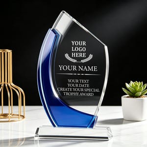 May include: A clear and blue glass award trophy featuring a flame-like shape on a rectangular base. The front surface is etched with the text: YOUR LOGO HERE, YOUR NAME, YOUR TEXT, YOUR DATE, CREATE YOUR SPECIAL TROPHY AWARD, and a laurel wreath.