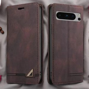 May include: A dark brown leather-style wallet phone case shown from the front and back. The front features a small triangular metal emblem at the bottom, while the back displays a rectangular cutout for the camera module with three lenses.
