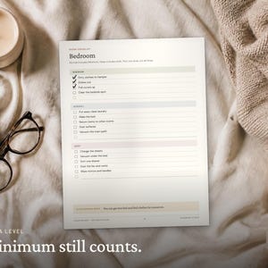 May include: A white paper checklist titled Bedroom with sections for Minimum, Normal, and Deep cleaning tasks. The list includes checkboxes and text such as Dirty clothes to hamper, Dishes out, and Pull covers up. The document is printed on white paper.