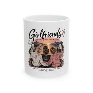 May include: A white ceramic mug featuring a graphic of three people sitting together facing a sunset over a lake. The text reads Girlfriends, Good Friends Better Times Forever, and Life is Better with Girlfriends, along with smaller phrases on their shirts.