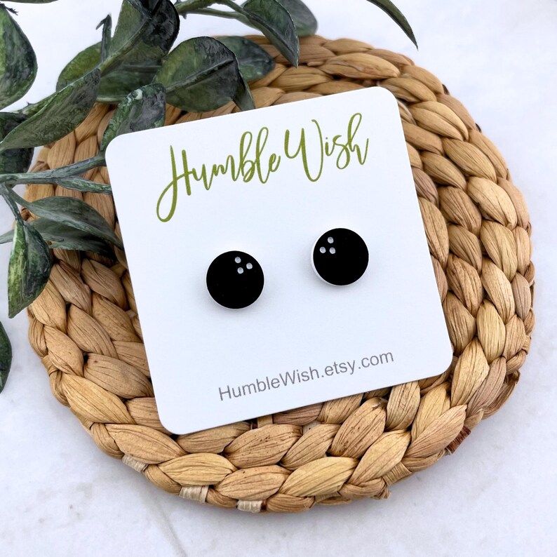 Peut inclure: Boucles d'oreilles clous en forme de boules de bowling noires sur une carte blanche avec le texte "Humble Wish" en vert. La carte repose sur un dessous de plat circulaire tress&eacute;. Le site HumbleWish.etsy.com est &eacute;galement imprim&eacute;.