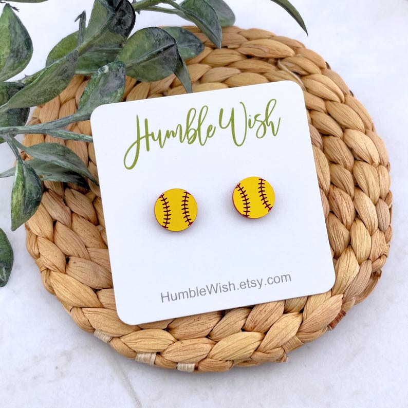 Peut inclure: Boucles d'oreilles clous en forme de balle de softball jaune avec des coutures rouges. Elles sont pr&eacute;sent&eacute;es sur une carte blanche avec le texte "Humble Wish" et "HumbleWish.etsy.com". Pos&eacute;es sur un dessous de plat tress&eacute;.