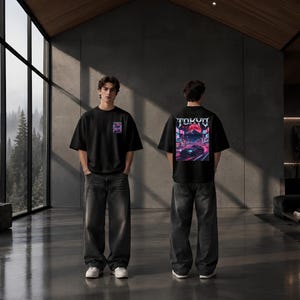 May include: A black short-sleeve t-shirt featuring a small graphic on the front chest and a large rectangular print on the back. The back graphic displays a car on a city street at night with the text TOKYO and a large red moon above.
