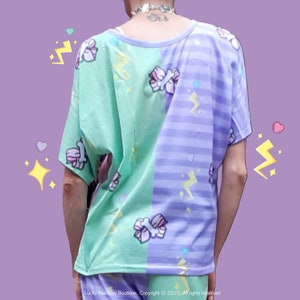 May include: A green and purple t-shirt with a split design. The left side is green with a light blue and pink candy cane pattern and the right side is purple with a light blue stripe pattern. Both sides have a white lightning bolt and heart pattern.