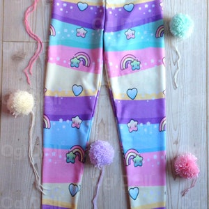 May include: A pair of colourful leggings with a rainbow, star and heart pattern. The leggings are made of a soft, stretchy fabric and are perfect for everyday wear.
