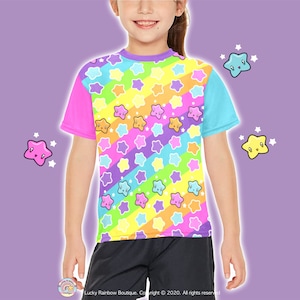 May include: A child wearing a colourful t-shirt with a rainbow stripe pattern and cute star designs. The shirt is made of a soft, comfortable material and is perfect for everyday wear.