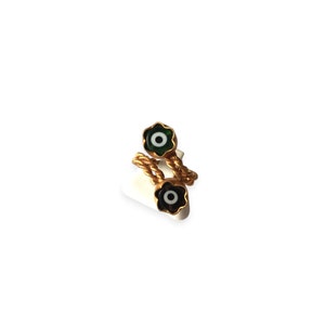 May include: Gold ring with two evil eye charms. The charms are green and black with white centers. The ring is twisted and has a rope-like design.
