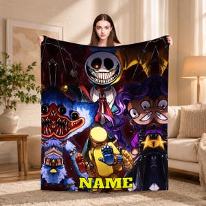Peut inclure: Une couverture rectangulaire en polaire avec une impression graphique vibrante représentant plusieurs personnages. Le motif inclut un bouffon souriant au centre, une créature bleue à fourrure, un robot jaune et un personnage aux cheveux violets avec le mot NAME.
