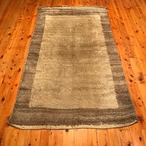 Puede incluir: Una alfombra rectangular con un centro verde claro y un borde verde oscuro. La alfombra est&aacute; colocada sobre un suelo de madera con vetas visibles.