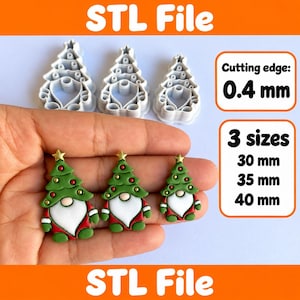 Può includere: Tre stampini per biscotti in plastica bianca a forma di gnomo albero di Natale e tre ornamenti in argilla finiti in verde, rosso e bianco. Il testo indica STL File, bordo di taglio da 0,4 mm e tre dimensioni: 30 mm, 35 mm e 40 mm.