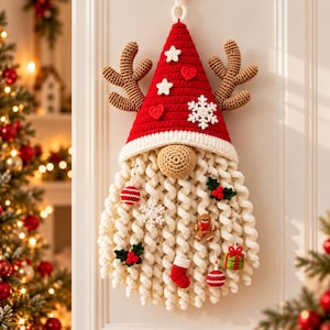 May include: A crocheted Christmas gnome wall hanging featuring a tall red hat with a white brim, brown antlers, and a long curly white beard. The hat is decorated with white stars, red hearts, and a snowflake. The beard holds small ornaments.
