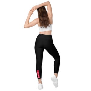 Peut inclure: Legging noir uni à taille haute avec un rectangle rouge vertical sur le bas de la jambe droite, portant l'inscription blanche CAMBERGE. Ce vêtement est ajusté, arrive au niveau des chevilles et présente une finition en tissu opaque et lisse.