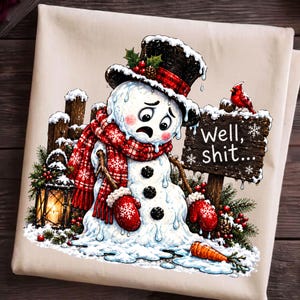 May include: A cream-colored fabric featuring a graphic of a melting snowman wearing a black top hat and red plaid scarf. The snowman has a distressed expression, red mittens, and a carrot nose on the ground. A sign reads Well, shit...