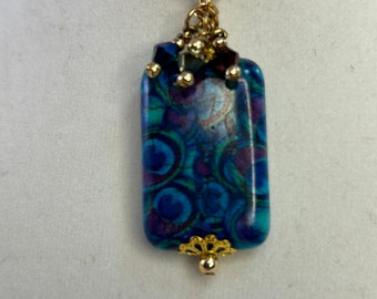 Peacock Patterned Pendant - A Beaded Pendant Featuring a Rectangular Focal Bead with Avian-Inspired Swirls of Color