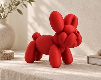 May include: A bright red sculpture shaped like a dog made of twisted balloons. The figure features a rounded body, four cylindrical legs, a small tail, and a head with two large upright ears and a snout, all rendered in a smooth matte finish.