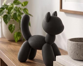 May include: A matte black cat figurine crafted with a smooth, rounded aesthetic that mimics the appearance of a balloon animal. The sculpture features a curved tail, pointed ears, and a solid, minimalist form standing on four cylindrical legs.