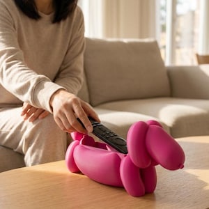 Peut inclure: Une figurine de chien rose vif, creuse, de style ballon, conçue comme un récipient de rangement. La forme du chien présente des segments arrondis et une finition mate lisse. Une télécommande de télévision noire est placée à l'intérieur.