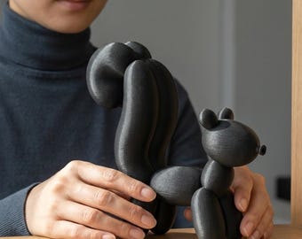 May include: A matte black squirrel figurine constructed from rounded, balloon-like segments. The sculpture features a prominent, curved tail, a small head with rounded ears, and a smooth, uniform texture throughout its entire form.
