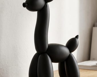 May include: A matte black sculpture shaped like a balloon animal giraffe with a long neck, rounded head, and four legs. The figure has a smooth, solid surface and is positioned next to two stacked books titled Modern Spaces and Sculptural Forms.