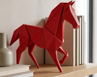May include: A bright red horse figurine featuring a geometric, faceted design that mimics the appearance of folded paper. The sculpture stands in a dynamic pose with one front leg lifted, showcasing sharp angular planes and a smooth matte finish.