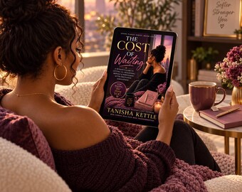 May include: A digital tablet displaying a book cover titled The Cost of Waiting by Tanisha Kettle. The cover features a person sitting, a mug, a notebook, and a candle. The tablet is held in front of a person wearing a dark purple textured sweater.