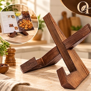 May include: A dark brown wooden book stand constructed from two interlocking pieces of wood forming an X-shape. The stand features a visible wood grain texture and angled supports designed to hold an open cookbook or tablet in an upright position.