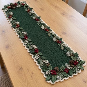 May include: A rectangular crochet table runner featuring a solid dark green center panel. The border is decorated with crocheted holly leaves, pine needles, small brown pinecones, and clusters of red berries, finished with a cream scalloped edge.