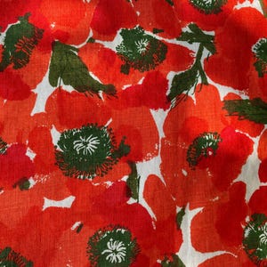 May include: A fabric featuring a vibrant floral pattern with large, overlapping red poppy flowers and dark green centers and leaves set against a white background. The print has a textured, painterly appearance with visible brushstroke details.