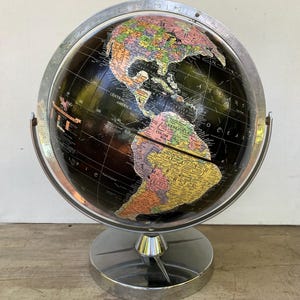 May include: A vintage globe with a black background and colorful continents. The globe is made of metal and has a silver stand.
