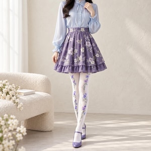 May include: A light blue long-sleeved blouse with a high collar and front buttons paired with a purple floral print skirt featuring a ruffled hem. The outfit includes white tights with a vertical purple floral pattern and purple Mary Jane shoes.