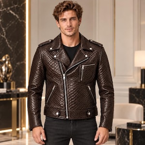 Puede incluir: Una chaqueta de moto de cuero marrón oscuro con un patrón texturizado similar a la piel de serpiente, que presenta un cuello ancho con muescas, cremalleras metálicas plateadas en el frente y bolsillo en el pecho, charreteras y botones a presión en el dobladillo.