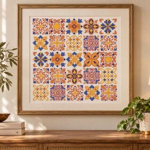Puede incluir: Una obra de punto de cruz enmarcada que presenta una cuadrícula de veinticinco azulejos cuadrados. Cada azulejo muestra un patrón geométrico o floral único en una paleta de colores vibrantes naranja, amarillo y azul sobre tela blanca.
