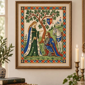 May include: A framed cross-stitch embroidery depicting a medieval scene with a woman in a green dress standing before a kneeling knight in blue armor. A white horse, a tree, a shield with fleur-de-lis, and a castle are visible in the background.