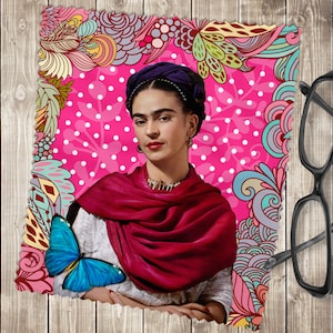 May include: A colourful illustration of Frida Kahlo with a blue butterfly on a pink background with white polka dots. The illustration is surrounded by a border of colourful flowers and swirls.